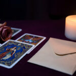 Composition symbolique avec des cartes ornées, une rose séchée, une enveloppe vierge et une bougie évoquant la réflexion après une rupture silencieuse.
